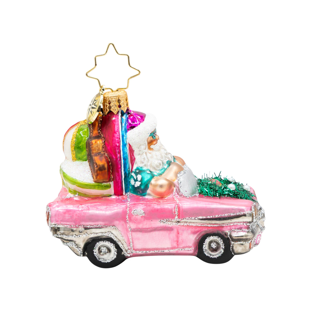 Santa in a pink convertible with a surfboard and beach gear glass Christmas ornament.