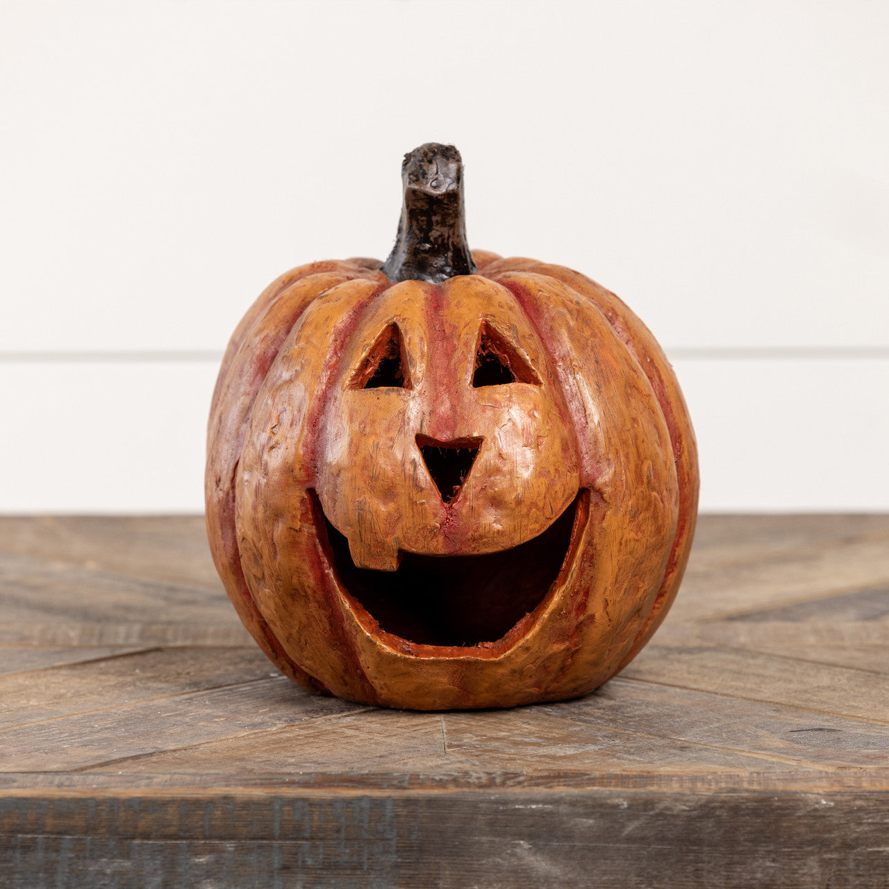 8-inch orange mache pumpkin with a large smiling mouth and triangular eyes on a wooden surface.