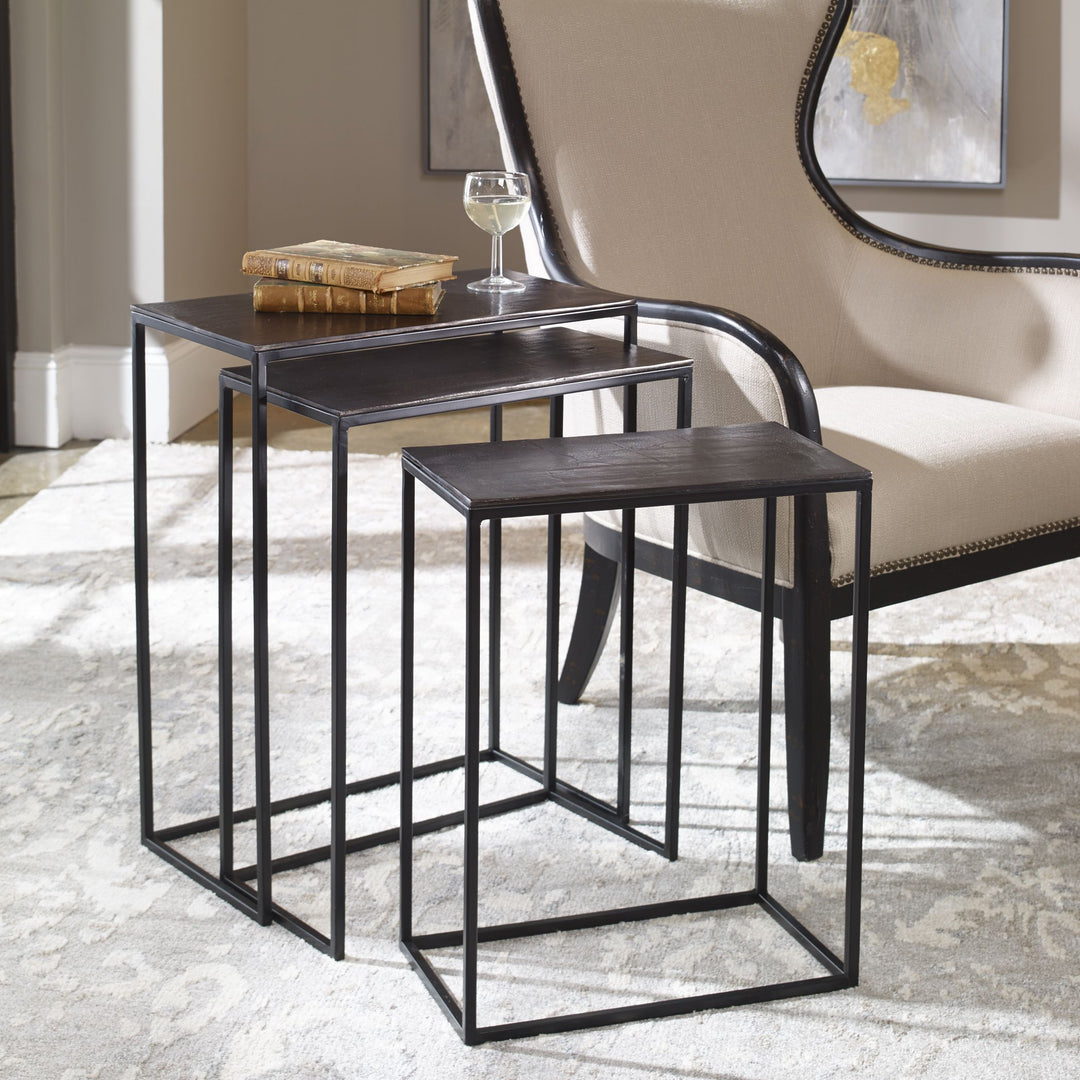 Three Coreene Iron nesting tables with dark finish and geometric cutout legs arranged together.