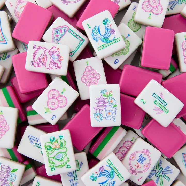 A pile of Amara Mahjong tiles featuring pink backs and white faces with colorful illustrations.
