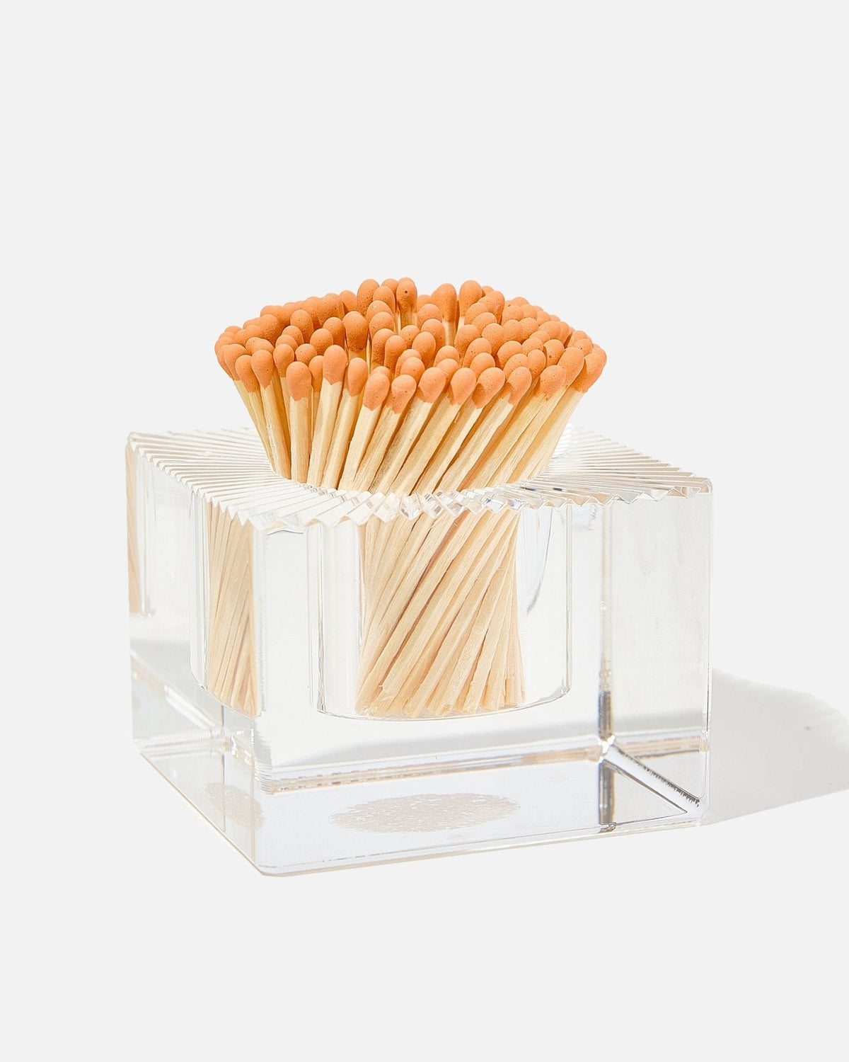 Clear glass square match striker filled with orange-tipped wooden matches.
