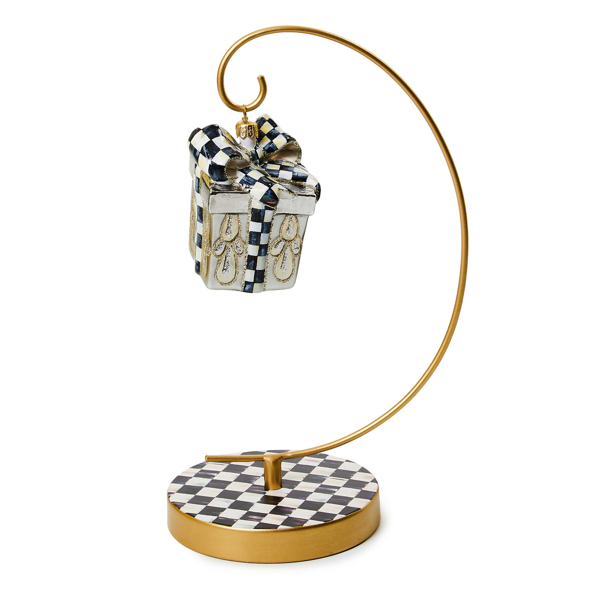 Gold-tone metal ornament stand with a black and white checkered base holding a gift box ornament.