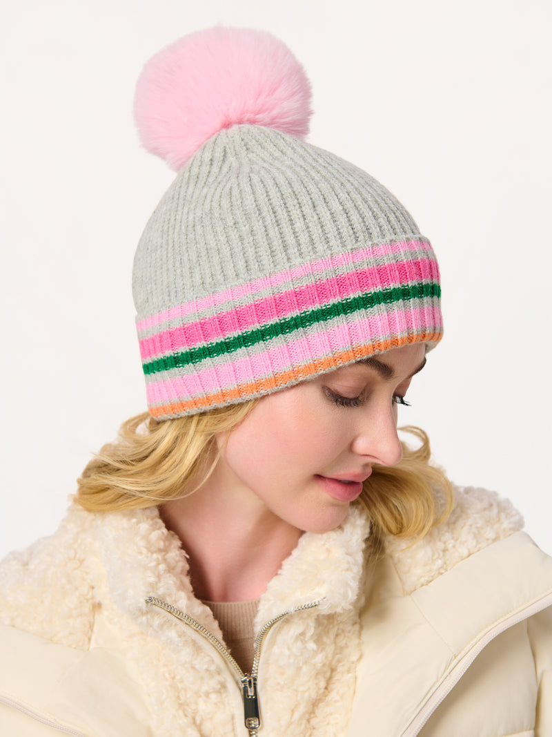 Woman wearing a gray ribbed Elle Beanie with pink, green, and orange stripes and a pink pom-pom.