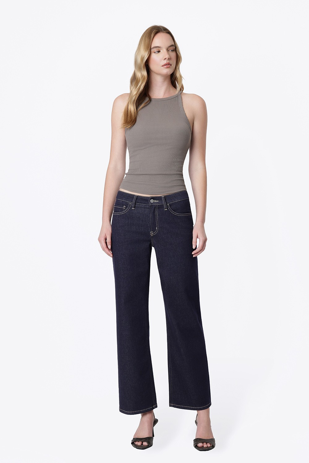 Woman wearing Alexa mid rise dark wash slim wide jeans with a grey ribbed halter tank top.