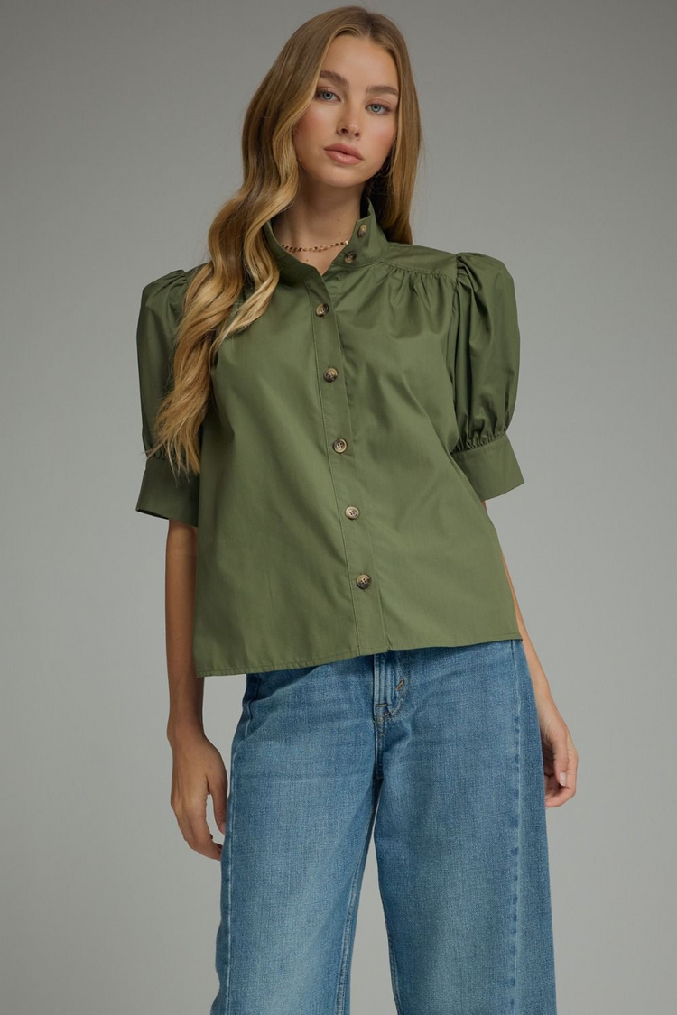 Woman wearing the Delia olive green short puff sleeve button-down top with blue jeans.