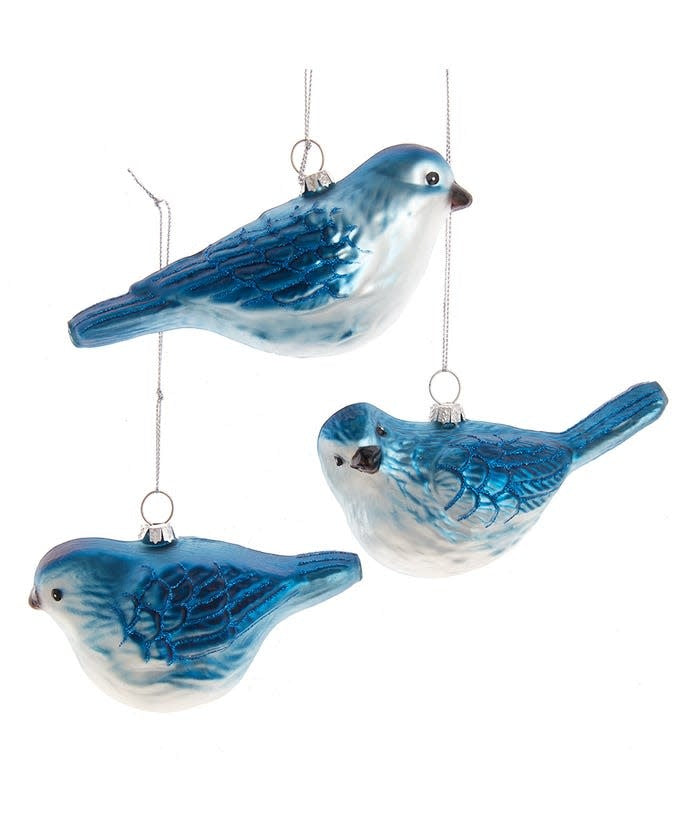 Glass blue bird ornament with white belly and glittered wings on a Christmas tree