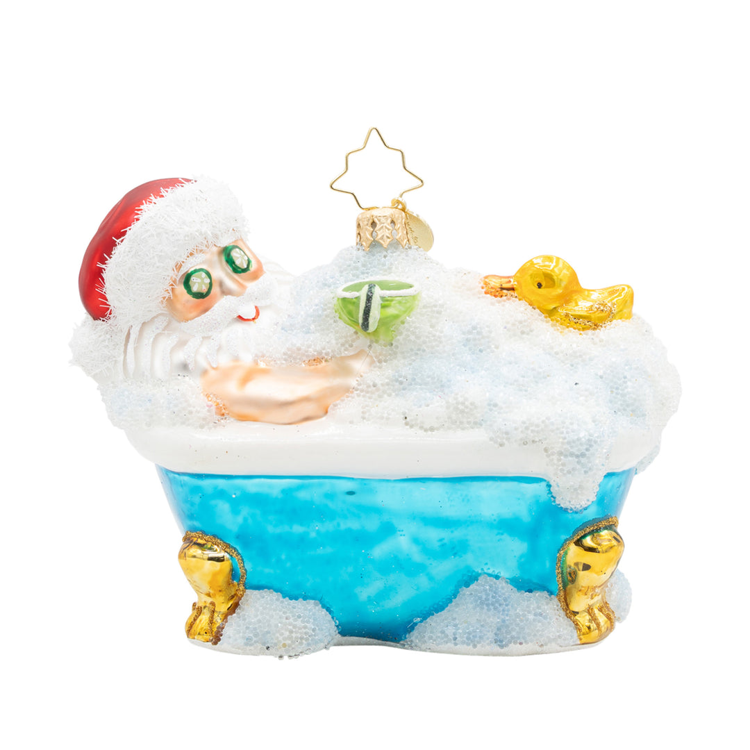 Glass ornament of Santa Claus relaxing in a blue bubble bath with a rubber duck and a green drink.