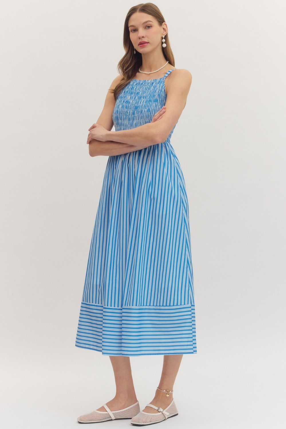 Woman wearing a blue and white Kenzie striped sleeveless midi dress with a smocked bodice.