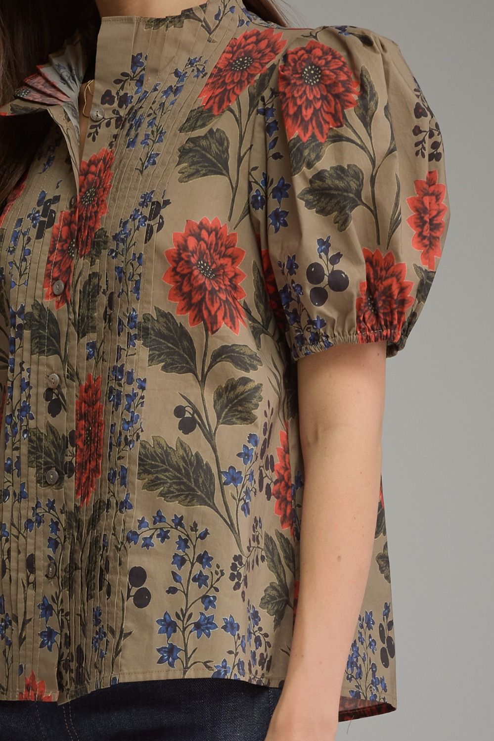 Close-up of a khaki floral top with red flowers, pintuck details, and short puff sleeves.