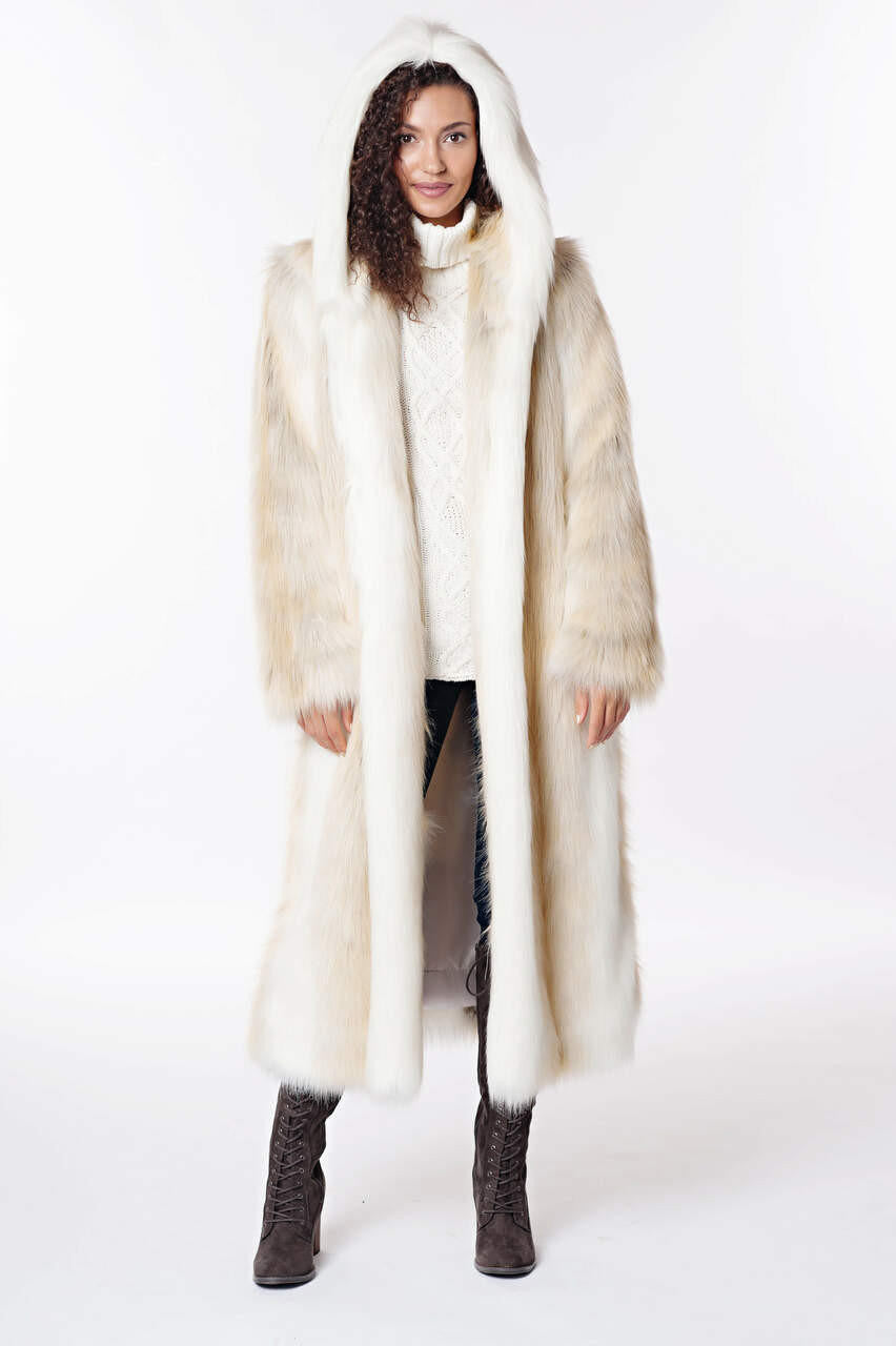 Woman wearing a long, hooded white and cream faux fur coat with a cable knit sweater and boots.