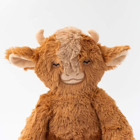 Close-up of a brown plush Yak Kin with small horns, floppy ears, and embroidered closed eyes.