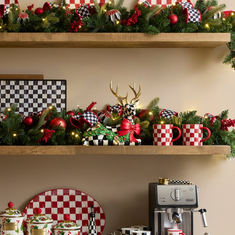 Holly Check Resting Deer figurine with gold antlers and a red bow on a decorated Christmas shelf.