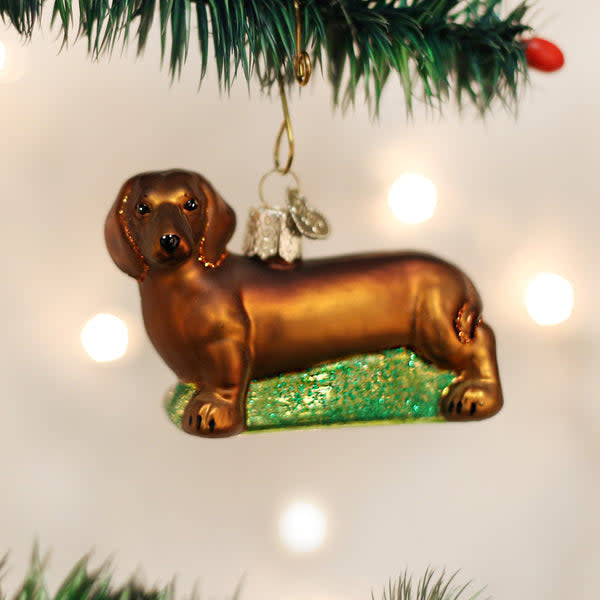 Red glass Christmas ornament shaped like a dachshund with black ears and tail.