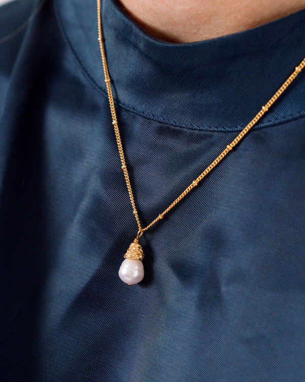 Dainty gold chain necklace featuring a single freshwater pearl drop pendant.