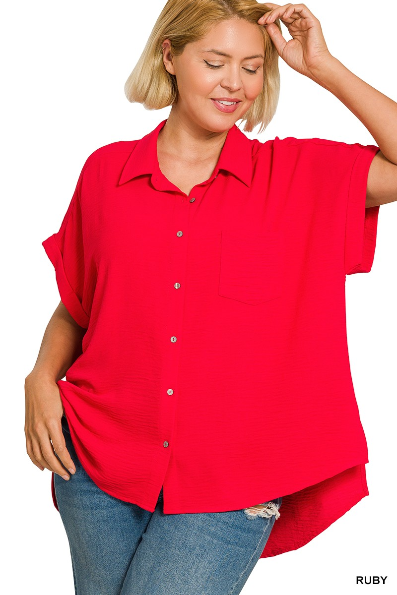 Woman wearing a ruby red plus size short sleeve button-down shirt with a hi-low hem and chest pocket.