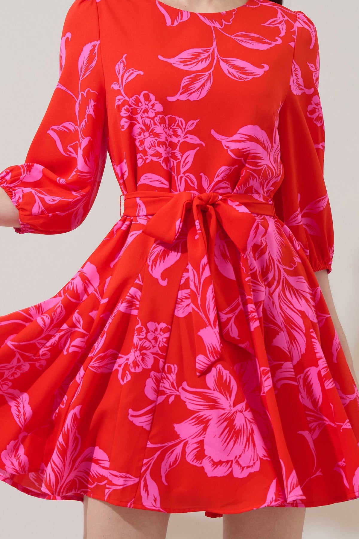 Red floral mini dress with balloon sleeves, fit-and-flare godet pleated skirt, and tie waist belt.