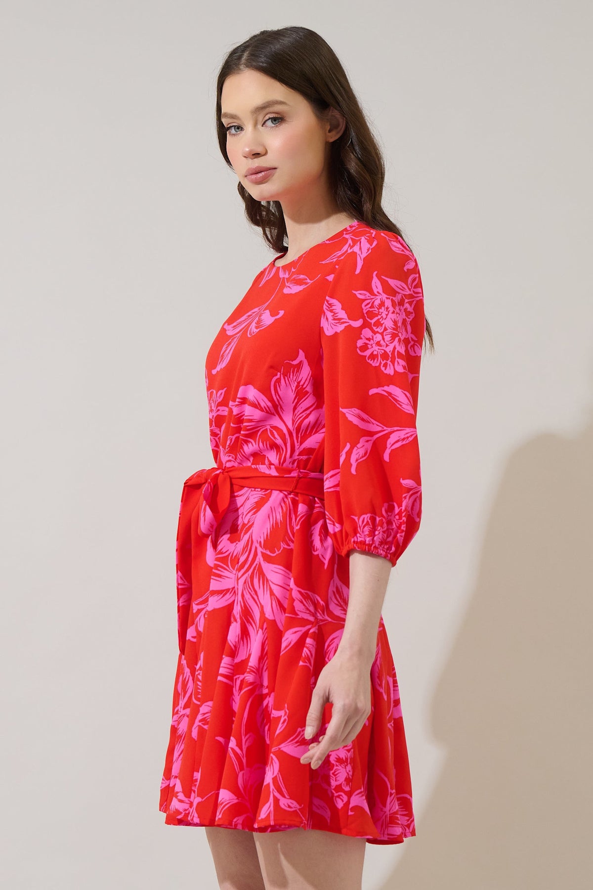 Red floral mini dress with balloon sleeves, fit-and-flare godet pleated skirt, and tie waist belt.