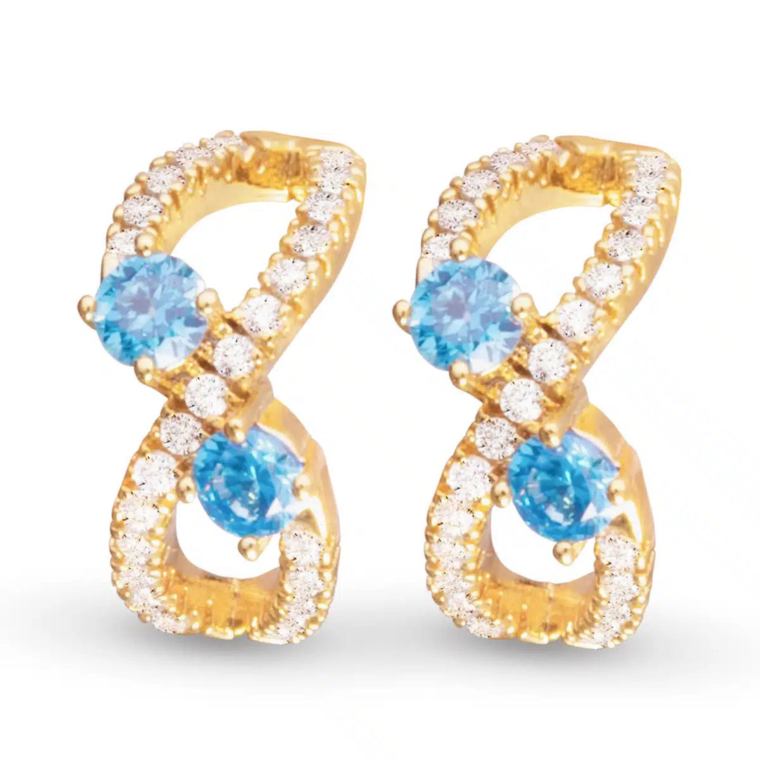 Gold infinity huggie earrings featuring clear and blue cubic zirconia stones.