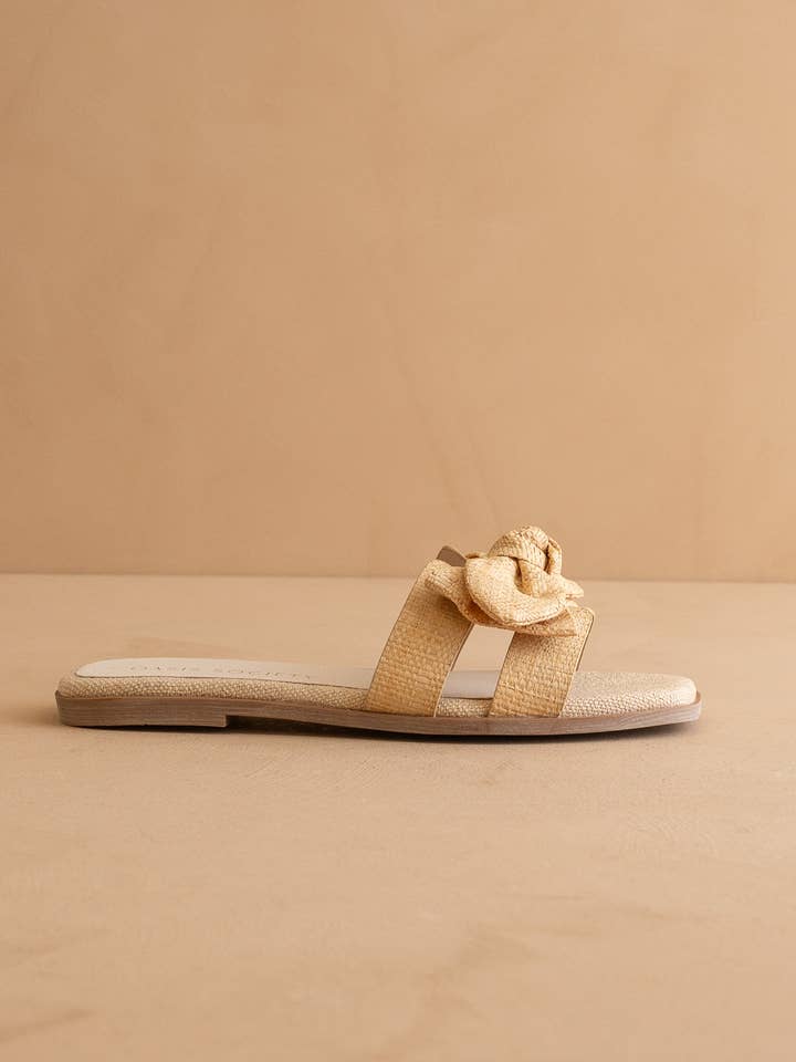 The Ginny Textured Bow Slide in a natural straw-like material with a cushioned sole.