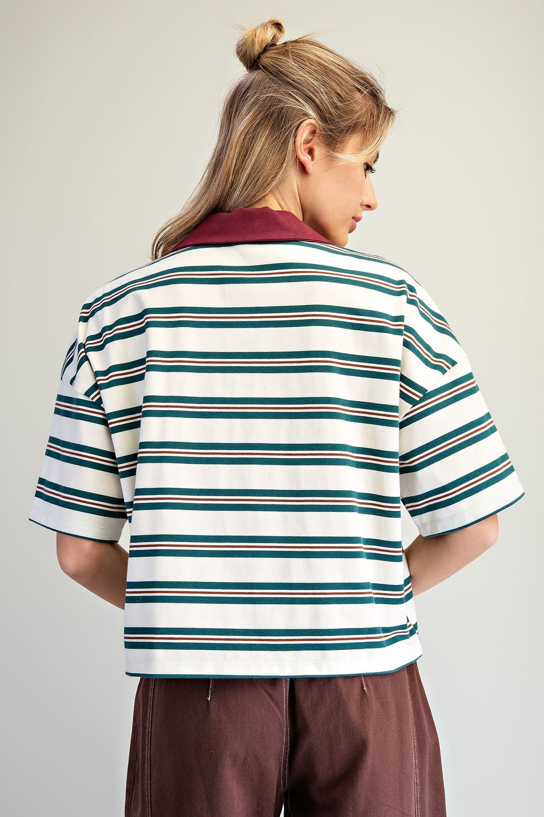 Back view of a boxy, oversized white polo top with forest green and brown horizontal stripes.