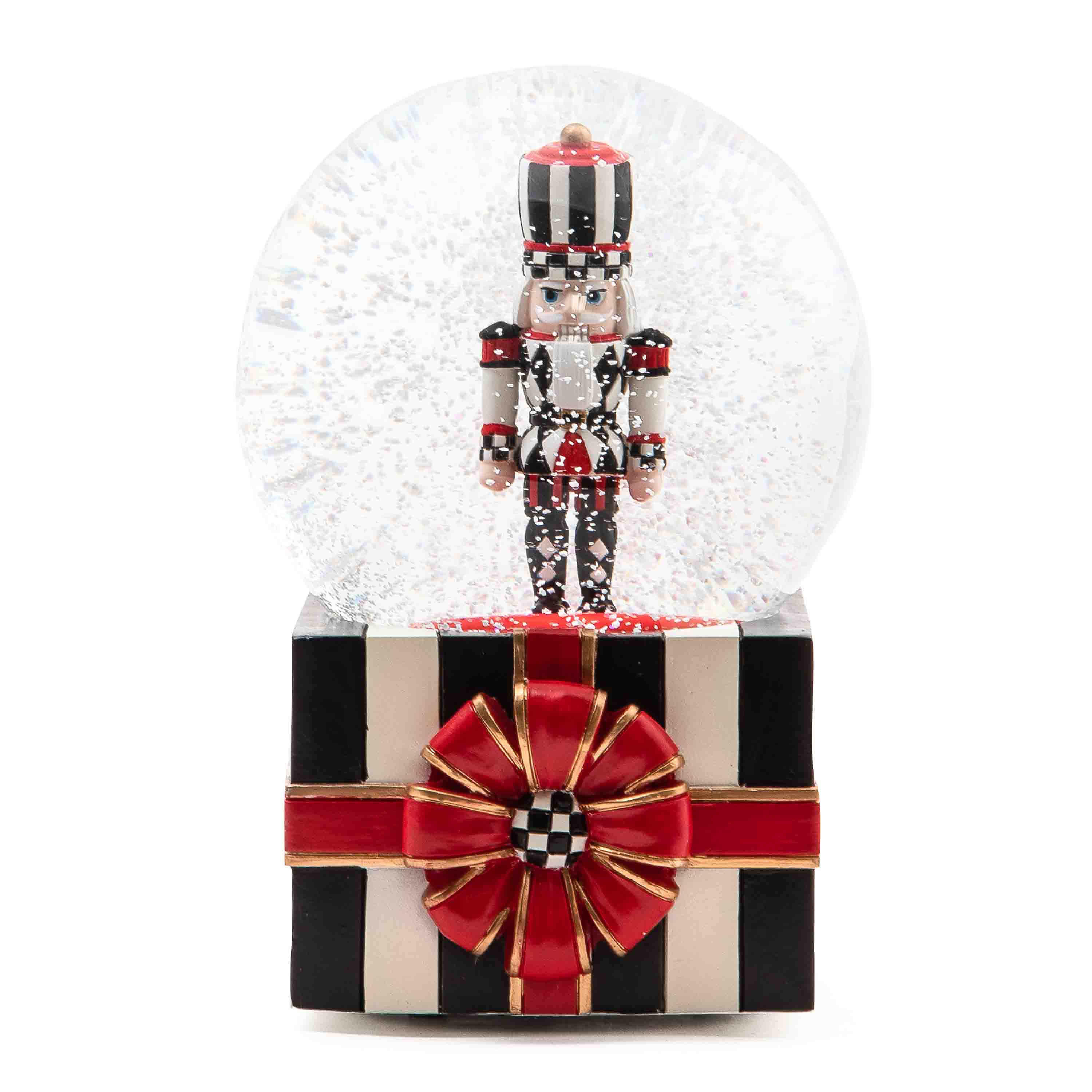 Nutcracker snow globe featuring a black and white striped base with a red bow and a nutcracker inside