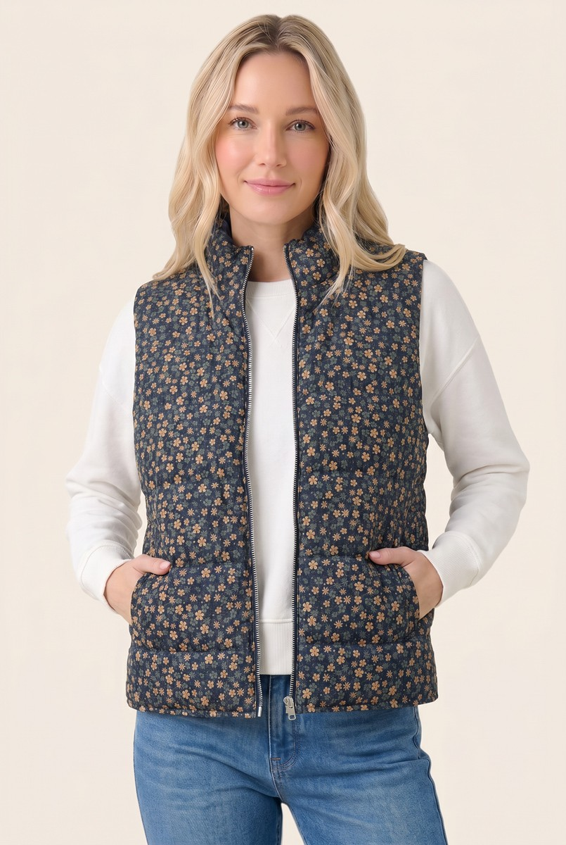 Woman wearing a Clara Corduroy Floral Printed Puffer Vest in navy with small orange flowers.
