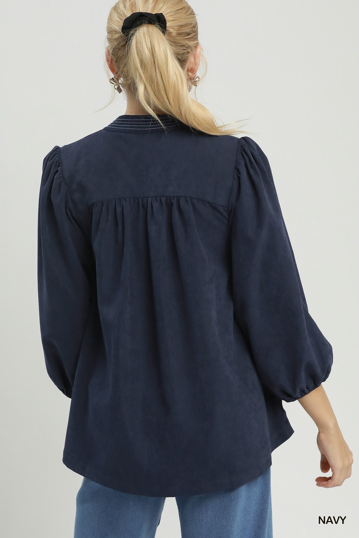 Back view of a navy sueded split neck blouse with gathered yoke and puff sleeves.