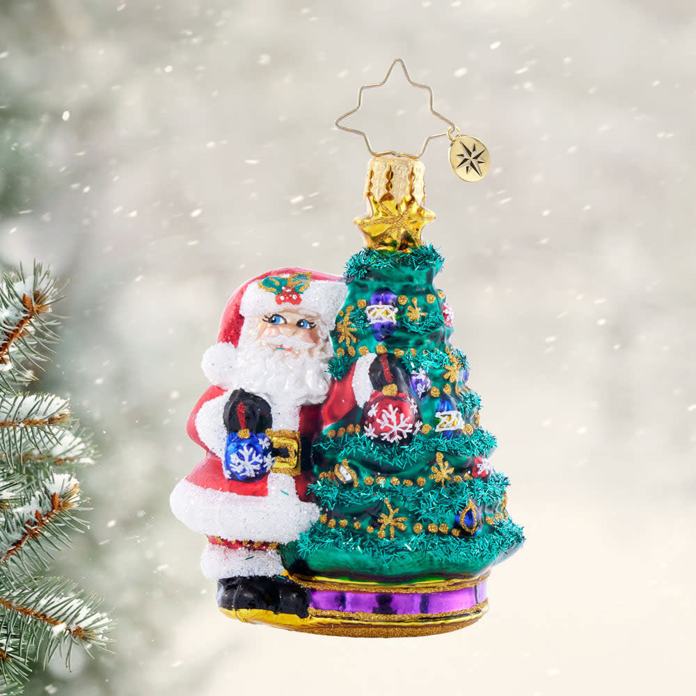 Santa figurine holding ornaments in front of a decorated Christmas tree