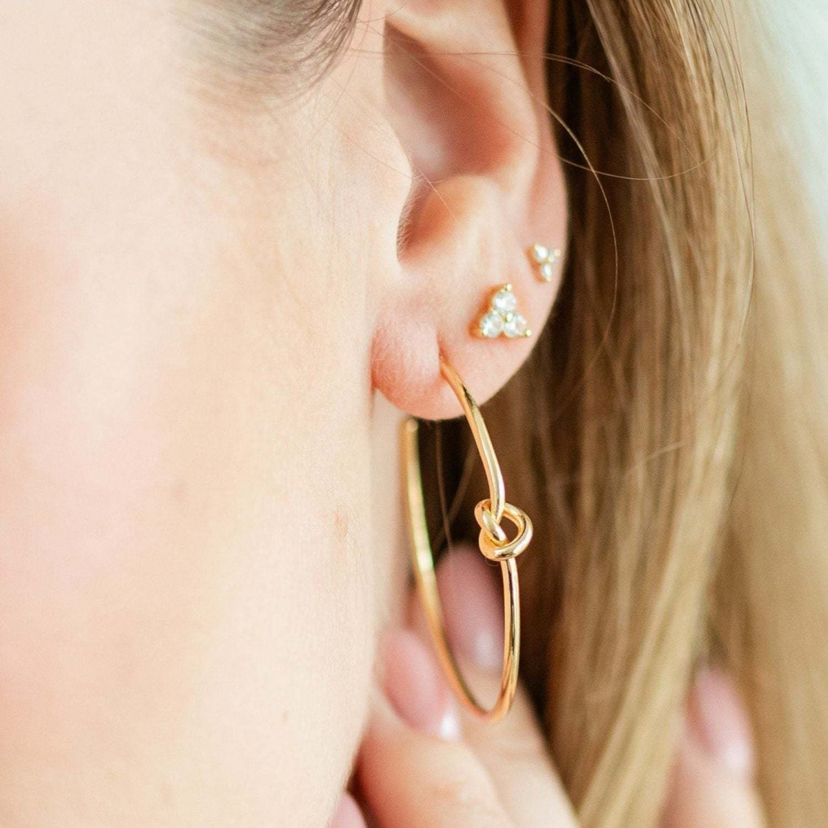 Brass hoop earrings with a delicate knot detail at the center.