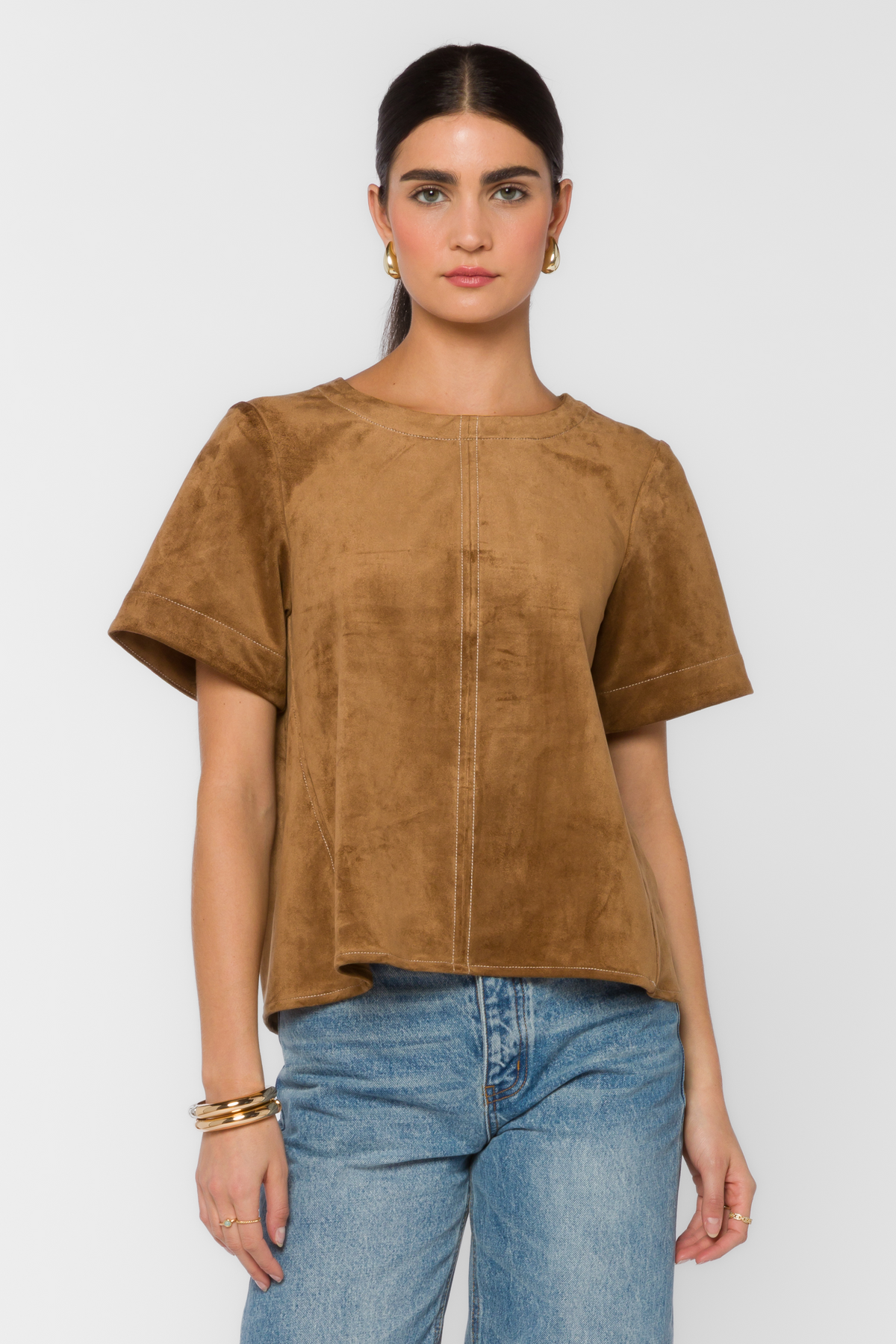Woman wearing the Juliette Top, a brown faux suede short-sleeve shirt with white stitch details.