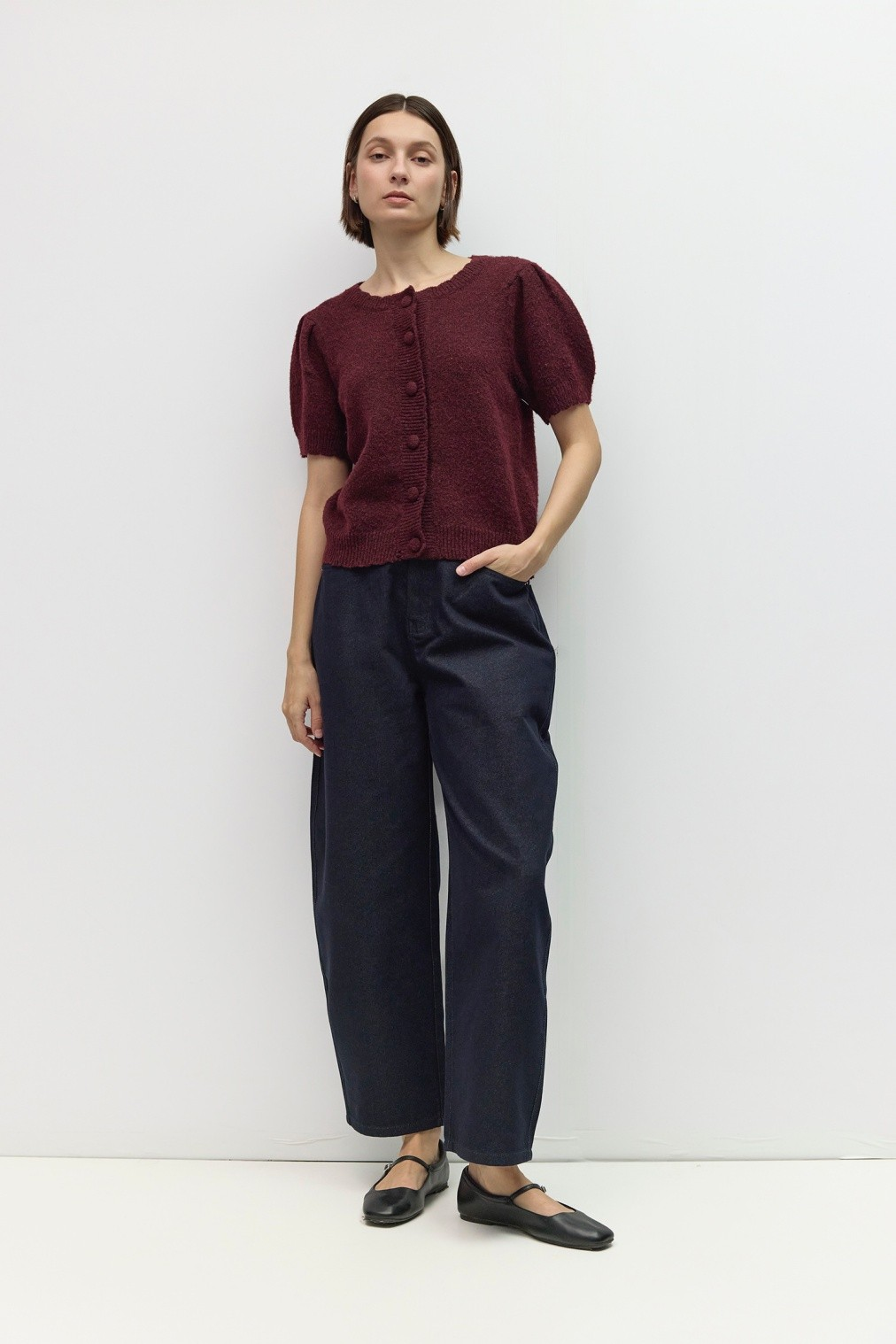 Woman wearing the Mary Kate Top, a burgundy short puff sleeve knit button-front top with dark jeans.