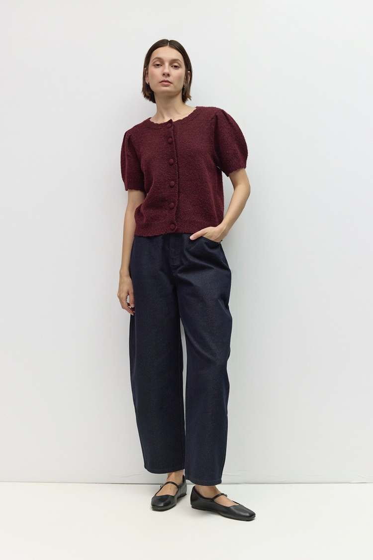 Woman wearing the Mary Kate Top, a burgundy short puff sleeve knit button-front top with dark jeans.