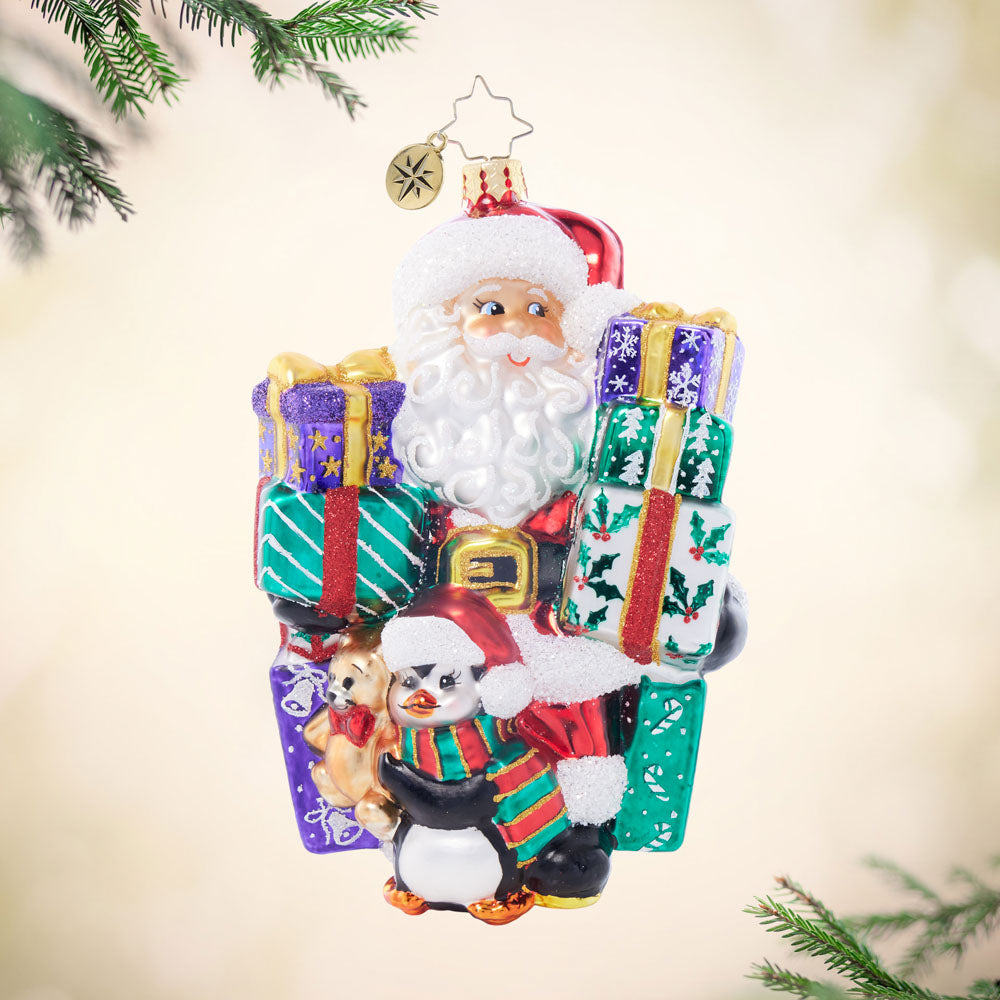 Santa’s Shopping Shenanigans glass ornament featuring Santa, a penguin, and colorful gift boxes.