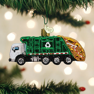 Glass garbage truck ornament with green body, recycling symbol, and gold hopper on a Christmas tree.