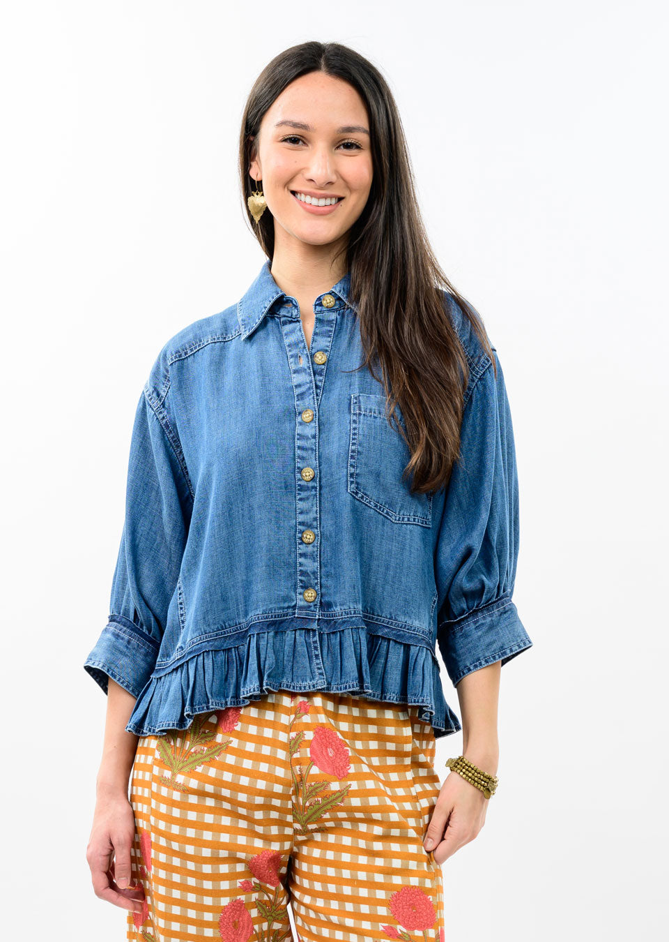 Woman wearing a blue denim jacket with a pointed collar, button-down front, and ruffle peplum hem.
