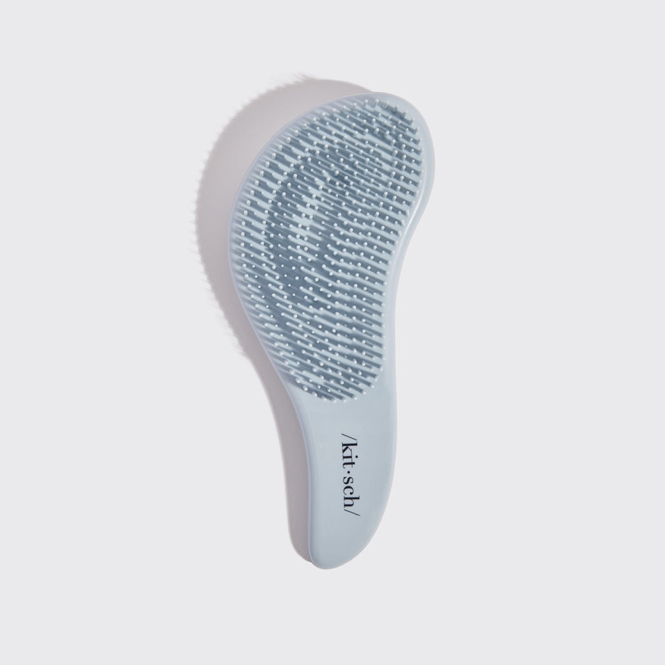 Black detangling brush with flexible bristles designed to smooth tangles.