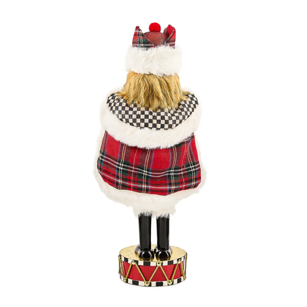 Back view of a Tartan Cardinal Nutcracker wearing a plaid cape and hat, standing on a drum base.