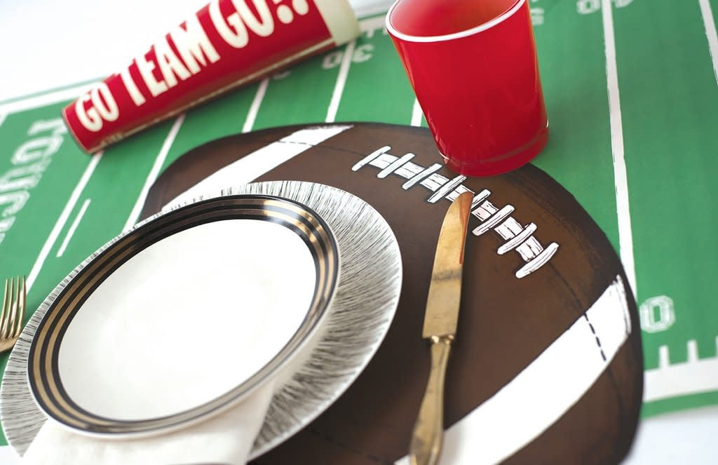 Set of twelve die-cut football-shaped placemats in green with white yard lines and numbers.
