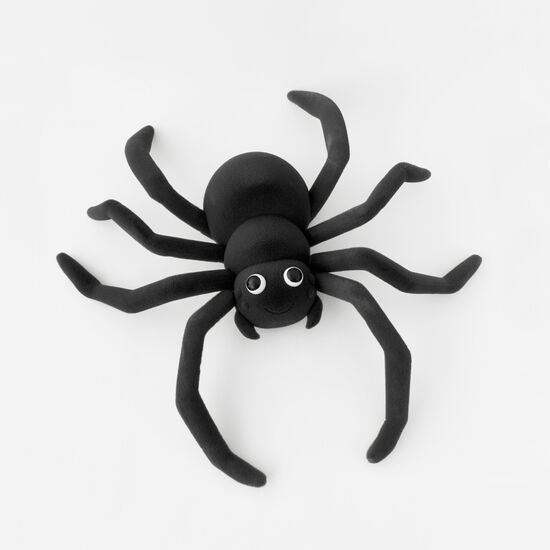 A large black flocked spider decoration with eight long legs and googly eyes on a white background.