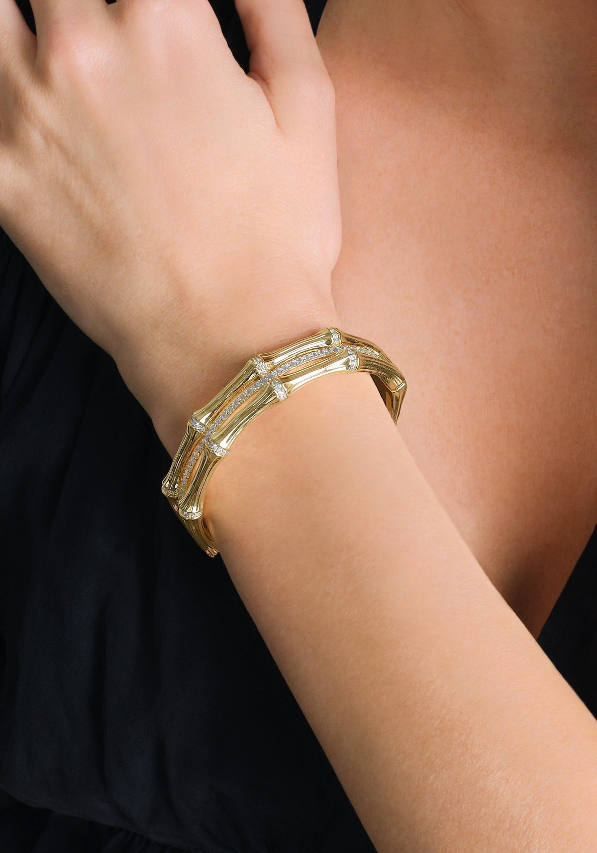 Woman wearing a gold-plated Bamboo Stacked Hinged Bangle with crystal pavé accents.