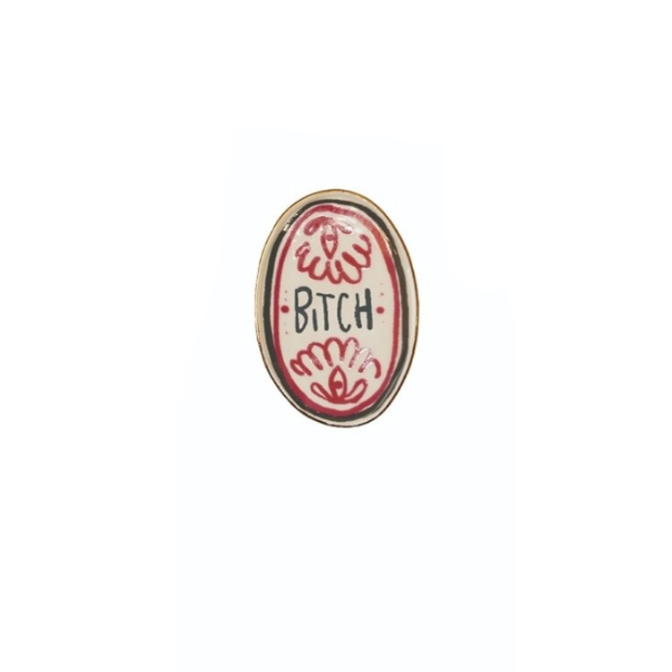 Oval stoneware magnet with red floral patterns and the word "BITCH" in black text.