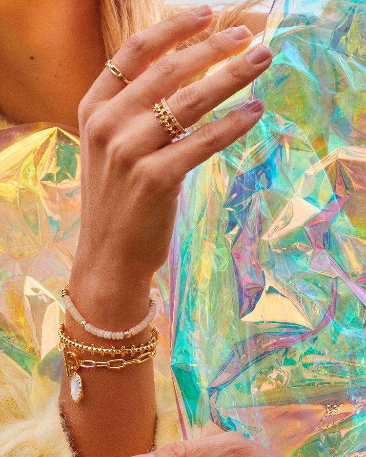 Close-up of a hand wearing the Deliah gold chain bracelet stacked with other jewelry.