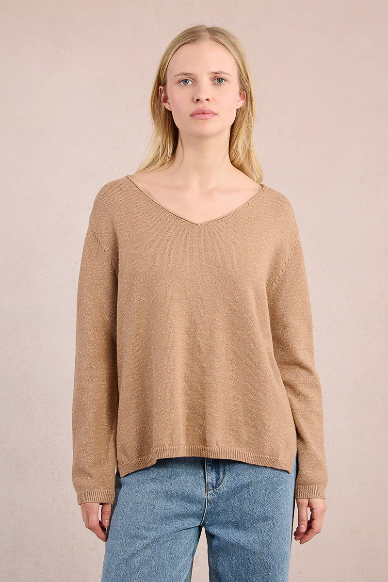 Woman wearing a Lesli Ladies Knitted Sweater in tan with a V-neckline and blue jeans.