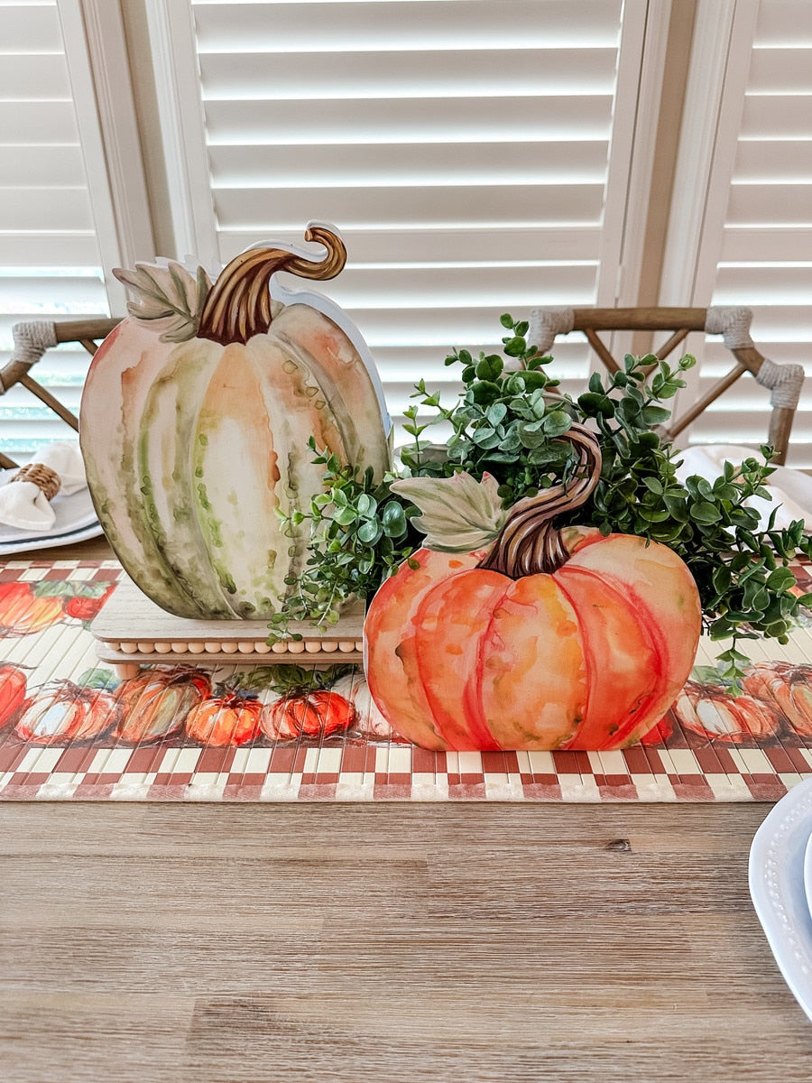 Two watercolor-style metal pumpkin pockets, one tall green and one short orange, with greenery.
