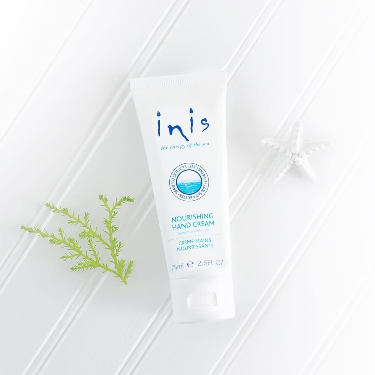 Inis Nourishing Hand Cream in a white jar with gold lid against a neutral background.