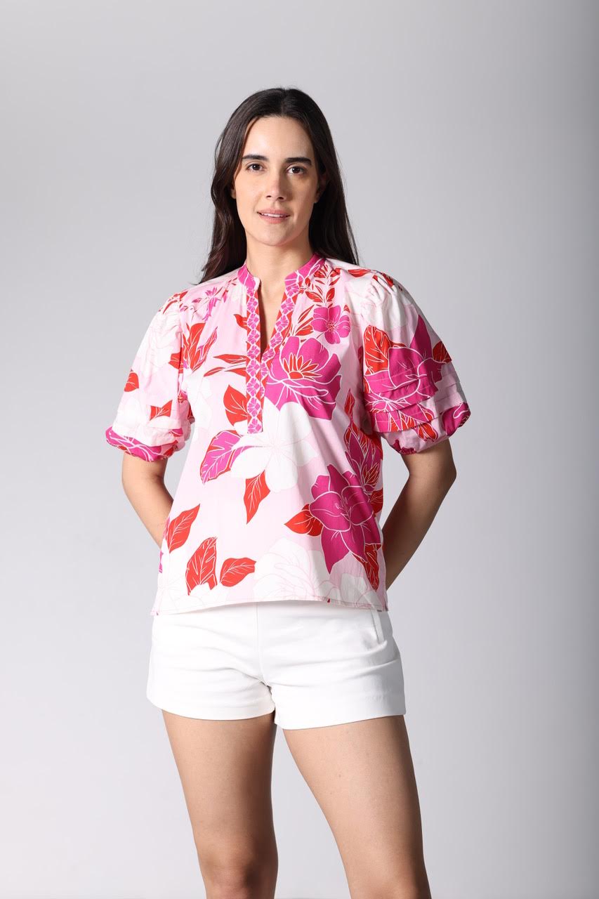 A woman wearing a pink floral Raya top with puff sleeves and a split neckline.