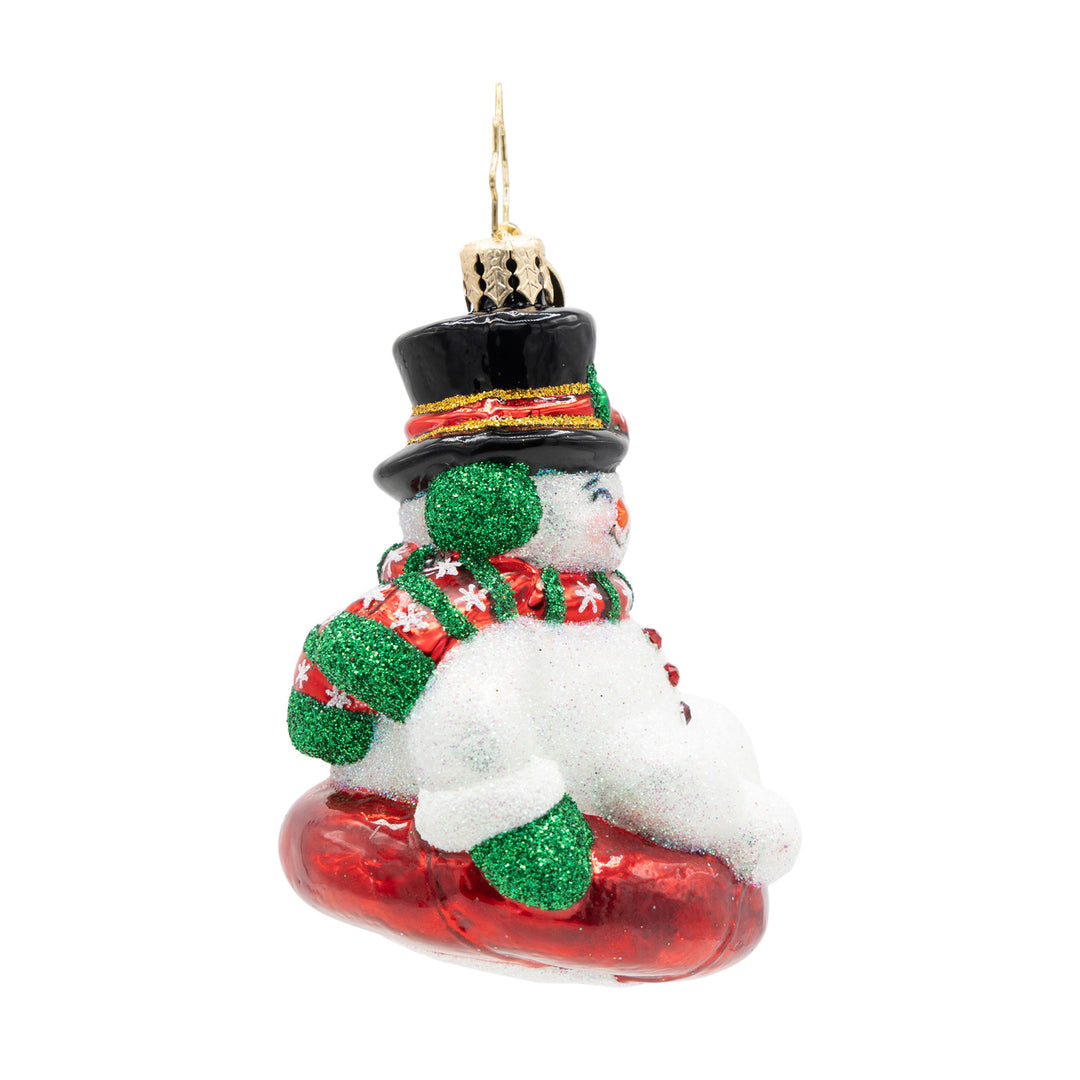 Snowman Christmas ornament wearing a top hat and scarf, riding a red snow tube.