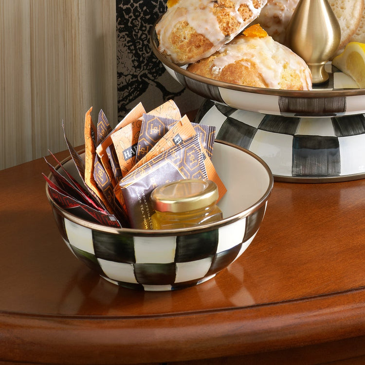 Courtly Check Enamel Everyday Bowl filled with tea packets and a small honey jar on a wooden table.