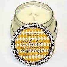 A white glass jar containing a Tyler Candle with a black wick.