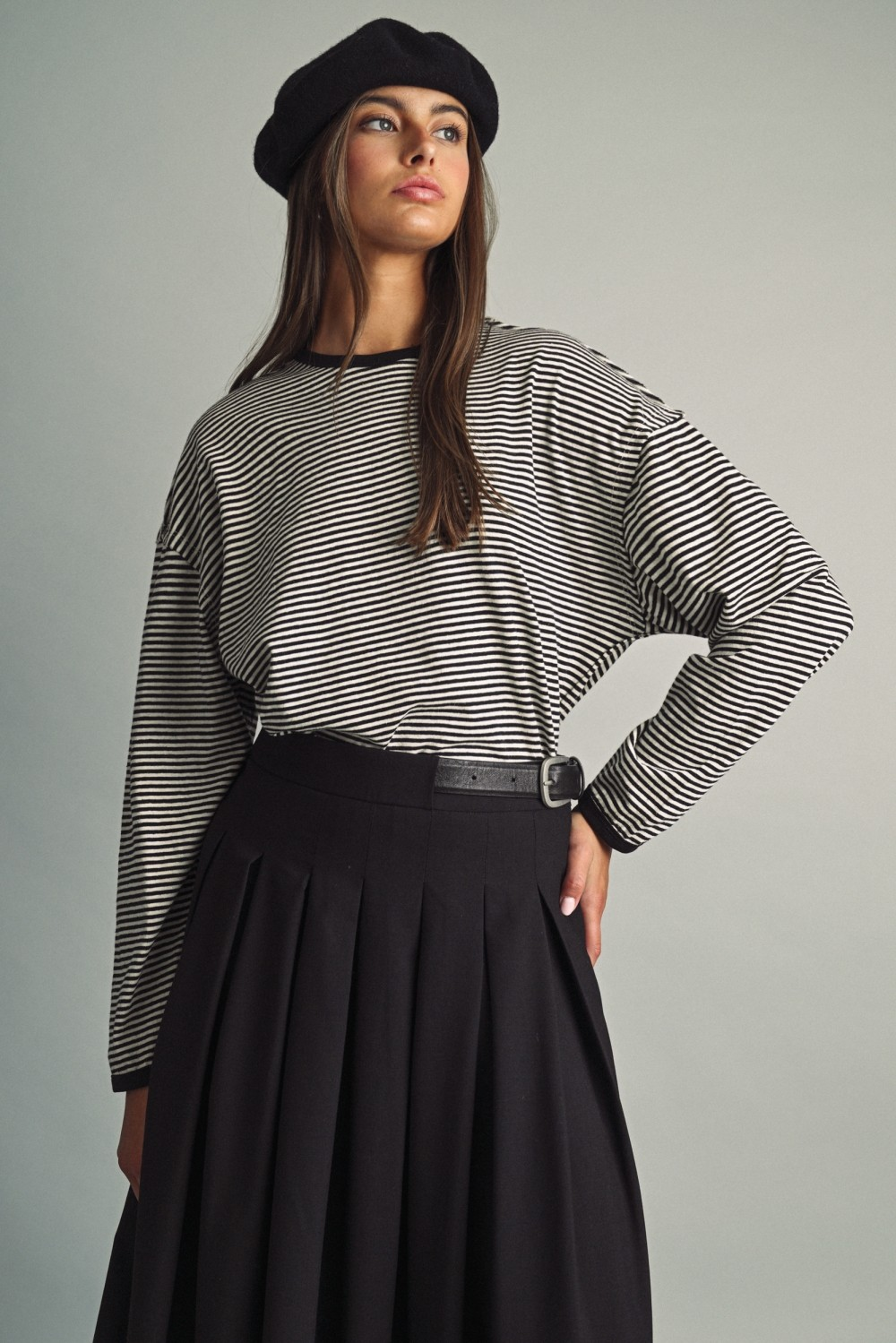 Woman in Alice Thin Striped Long Sleeve Light Top, black pleated midi skirt, and a beret.